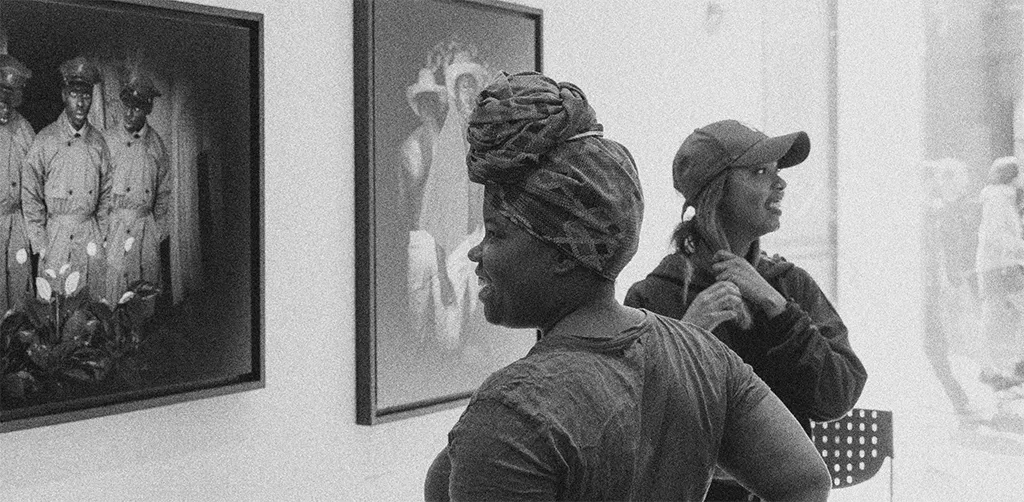 Two women looking at framed photographs in a gallery.
